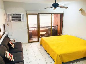 a bedroom with a yellow bed and a couch at Increíble Depa Frente al Mar in Mazatlán