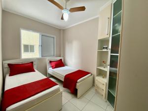 Duas camas num pequeno quarto com almofadas vermelhas em Residencial Santo Expedido na Praia Grande