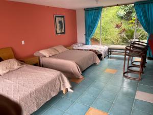 a room with three beds and a window at Hotel Familiar El Remanso Del Agua in Guatapé