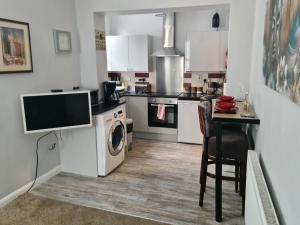 a kitchen with a washing machine and a table with a tv at Cozy apartment 1 in Worcester
