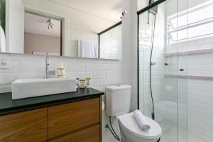 a bathroom with a toilet and a sink and a shower at Prédio com apartamentos completos, com piscina e a passos da praia - Agua Marinha in Florianópolis