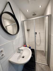 a bathroom with a sink and a shower with a mirror at Cozy Apartment with WIFI, Near University&Hospital in Augsburg