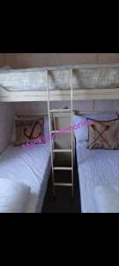 two bunk beds with white sheets and a ladder at Mackies Memories. in Hemsby