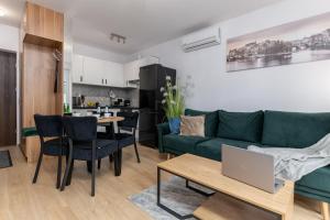 a living room with a green couch and a table with a laptop at Apartament Sowa Deluxe in Bielsko-Biala