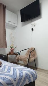 a bedroom with a chair and a tv on the wall at Matei Petra in Lugoj