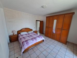 een slaapkamer met een bed, houten kasten en een tegelvloer bij VILLA AIDA LAKE VIEW in Lavena Ponte Tresa