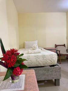 1 dormitorio con 1 cama y un jarrón de flores sobre una mesa en Hotel Bigu, en Puerto Escondido