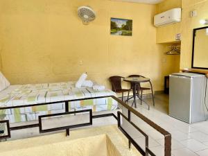Habitación con 2 camas, mesa y nevera. en Hotel Bigu, en Puerto Escondido