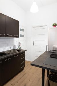 kuchnia z czarnymi szafkami, stołem i lodówką w obiekcie ClickTheFlat Aleje Niepodległości Center Apart Rooms w Warszawie