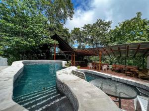 a swimming pool with two chairs and a table at Hotel La Colina in Manuel Antonio