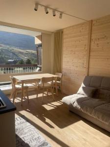 a living room with a table and a bed and a balcony at Appartement deux alpes pied des pistes in Les Deux Alpes