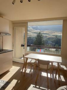 a kitchen with a table and chairs and a large window at Appartement deux alpes pied des pistes in Les Deux Alpes