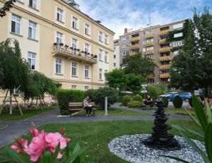 a park with people sitting on a bench in front of buildings at Centrum Salvator in Bratislava