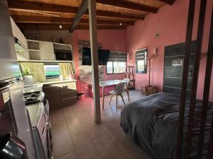 1 dormitorio con paredes rosas, mesa y cama en Monoambiente vistasalolivia Ushuaia en Ushuaia