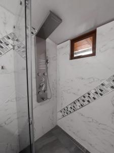 a bathroom with a shower with white marble at Casa y Flores in Baños