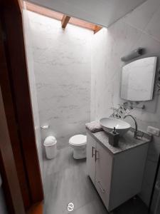 a white bathroom with a sink and a toilet at Casa y Flores in Baños