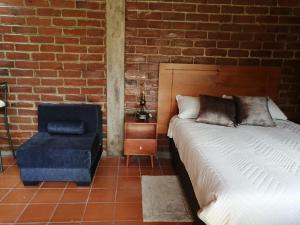 a bedroom with a bed and a blue chair at Casa y Flores in Baños