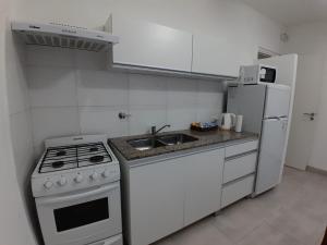a white kitchen with a stove and a refrigerator at TresA -1- in Tres Arroyos +12 photos
