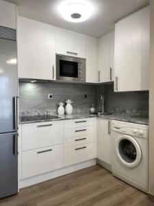 马德里Acogedor apartamento的配有白色橱柜和洗衣机的厨房
