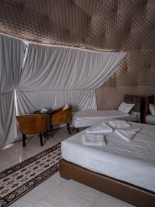 1 dormitorio con 2 camas, escritorio y mesa en SUN LUXURY CAMP &Tour, en Wadi Rum