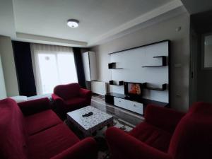 a living room with red chairs and a flat screen tv at البيت المثالي in Kırac
