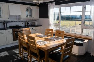 a kitchen with a wooden table and chairs and a window at Atlantic views at Arnisdale House on Lewis in Brue