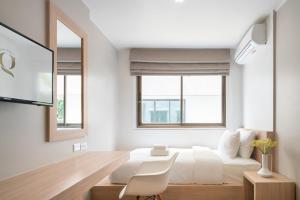 a bedroom with a white bed and two windows at G Boutique Silom Hotel in Bangkok
