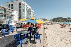 Melhores lembranças Prédio a Beira Mar na Prainha. في أرايال دو كابو: مجموعة من الكراسي والطاولات ومظلة على الشاطئ