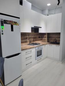 eine Küche mit weißen Schränken und einem weißen Kühlschrank in der Unterkunft Comfortable 2-roomed apartment Ozod Apartments SU2 in Samarkand