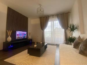 a living room with a couch and a tv at "Olympic Sweet Home" Paris Stade de France in Épinay-sur-Seine
