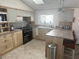 La cuisine est équipée de placards en bois et d'une cuisinière noire. dans l'établissement Luxury 6-8 Berth Lodge, à New Milton