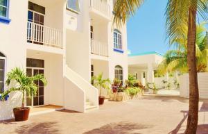 a white building with palm trees in the courtyard at Corales Suites in Puerto Morelos