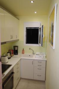 a kitchen with white cabinets and a sink and a window at Best view in the Bay! in Athens