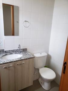 a bathroom with a toilet and a sink and a mirror at Spot Residence São Carlos 700m da USP in São Carlos