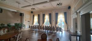 a large room with chairs and tables and windows at Gościniec & SPA Darłowo in Darłowo