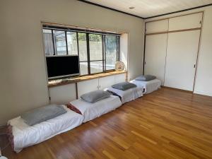 a room with three beds and a flat screen tv at みんなのふるさとウエダイラハウス in Konuma