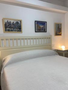 マドリードにあるMalasaña Palma Studiosの白いベッド1台と壁に2枚の絵が飾られたベッドルーム1室が備わります。