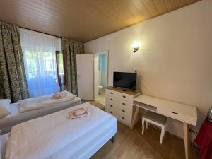 a room with two beds and a desk with a television at Country House & Restaurant Hronec in Hronec