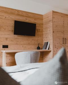 um quarto com uma televisão, uma cama e uma cadeira em Stoacherhof Apartments em Matrei am Brenner