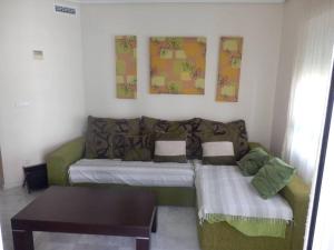 een woonkamer met een bank en een tafel bij Precioso apartamento en complejo residencial con piscina,barbacoa y pista de padel. in Villajoyosa