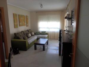 een woonkamer met een bank en een tafel bij Precioso apartamento en complejo residencial con piscina,barbacoa y pista de padel. in Villajoyosa