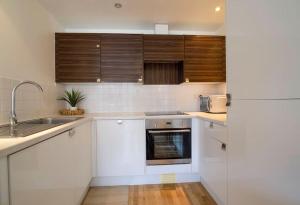 cocina con armarios blancos, fregadero y nevera en Perfect 1 bed flat en Londres