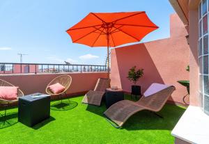 a patio with chairs and an umbrella and grass at Casa Pretori in Tarragona