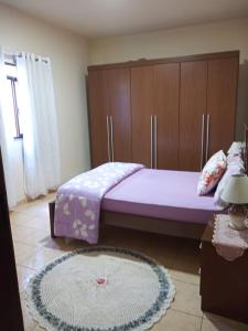 1 dormitorio con 2 camas, armarios de madera y alfombra en CASA DA LÉIA en Caparaó Velho