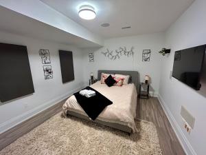 a bedroom with a bed and a tv on the wall at Boho-chic Spacious Basement Apartment in Toronto