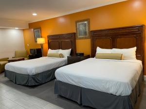 two beds in a hotel room with orange walls at Howard Johnson by Wyndham Ridgecrest, CA in Ridgecrest