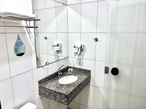 a bathroom with a sink and a mirror at Hotel Golden JK in Muriaé