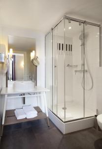 uma casa de banho com um chuveiro e um lavatório. em Hôtel du Triangle d'Or em Paris