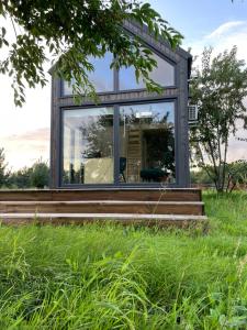 een glazen huis in een veld met gras bij Your Cute Hytte in Smołdzino
