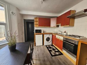 uma cozinha com uma mesa, um fogão e uma máquina de lavar louça em Family room near Queen Mary College em Londres